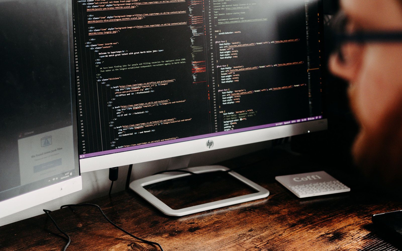 A developer working on application source code across desktop monitors